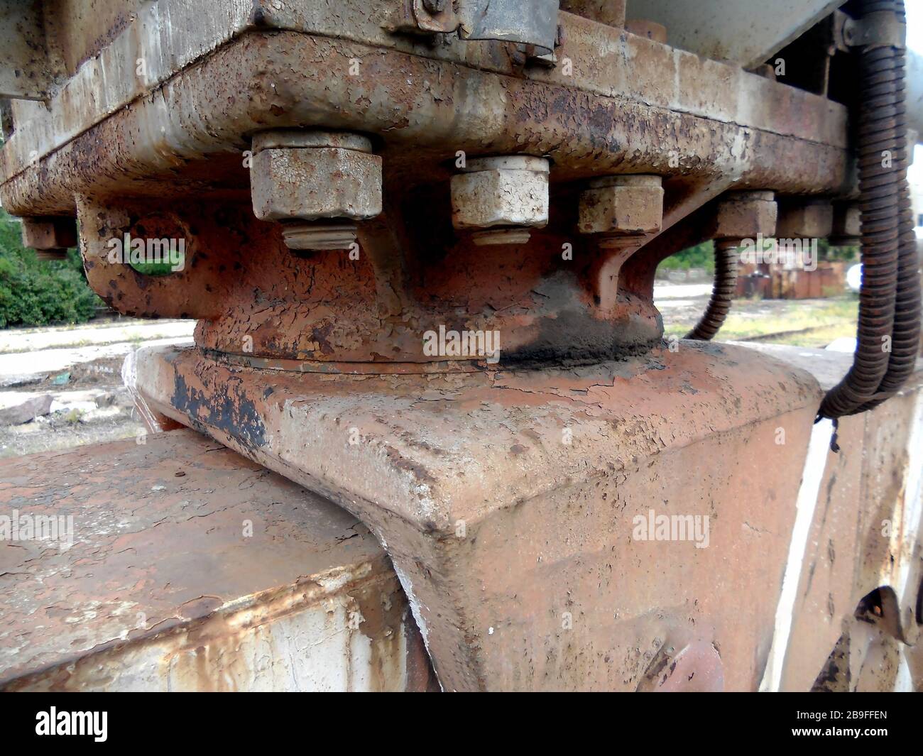 Old steel bolts and rusty nuts on a support beam plate. Structural detail of the base of a