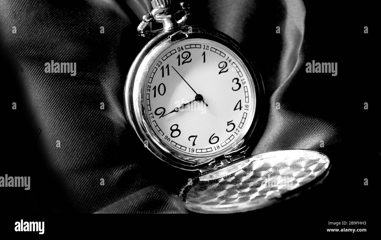 Old antique pocket watch showing time on black material close up. Black