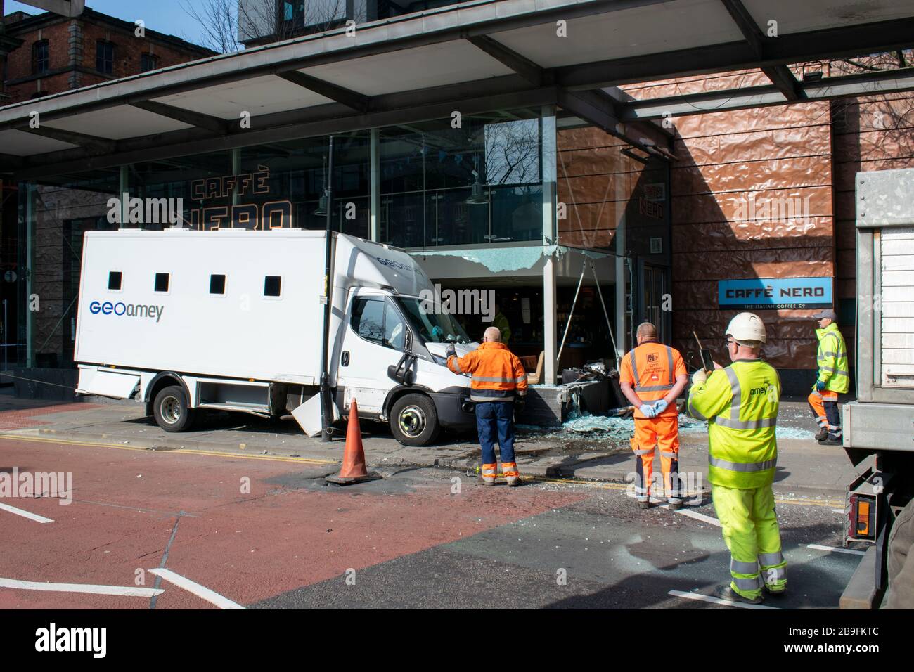 A Geoamey prisoner escort van in collision with locked down Cafe Nero frontage on Portland Street central Manchester UK with recovery personnel. Stock Photo
