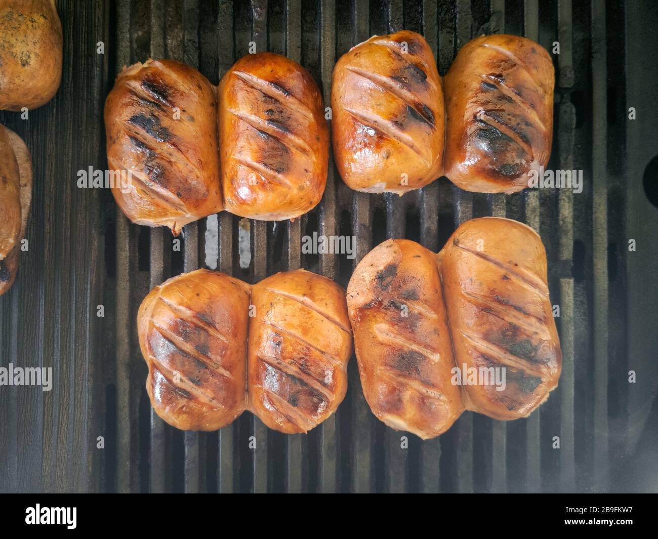 Four mouth-watering traditional bavarian Knackwursts from Regensburg cut in half roasted on cast iron grill grate Stock Photo