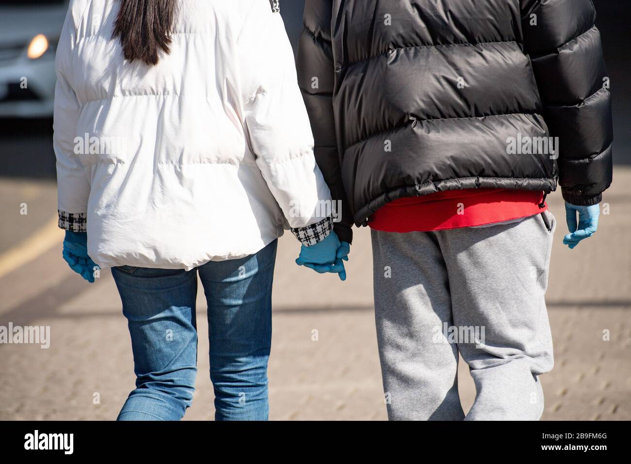 A couple hold hands whilst wearing protective gloves in Birmingham, the day after Prime Minister Boris Johnson put the UK in lockdown to help curb the spread of the coronavirus. Stock Photo