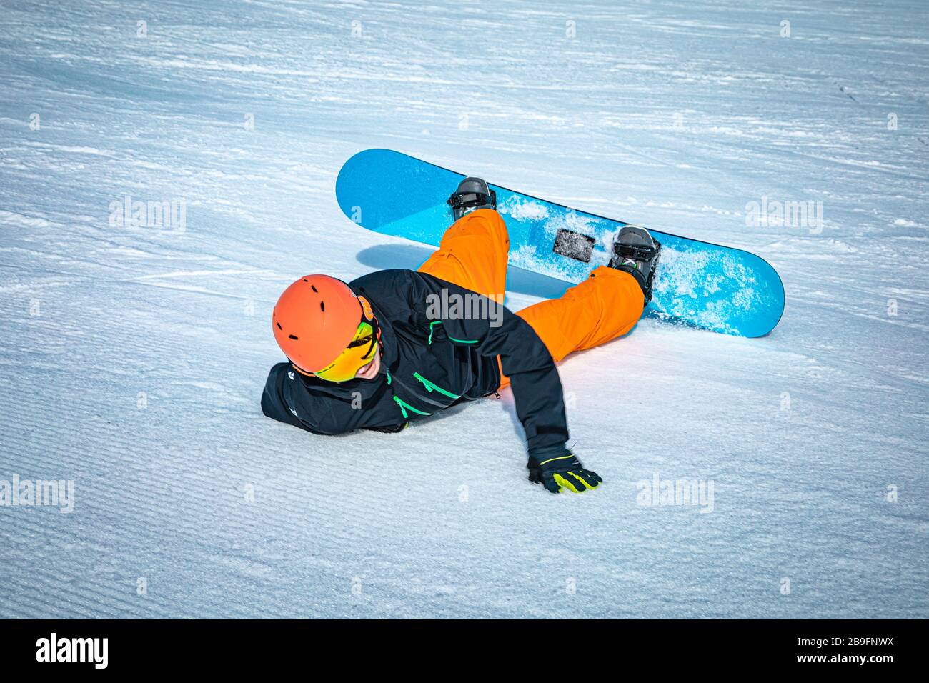 Teenage snowbarder falling down after losing control over his snowboard ...