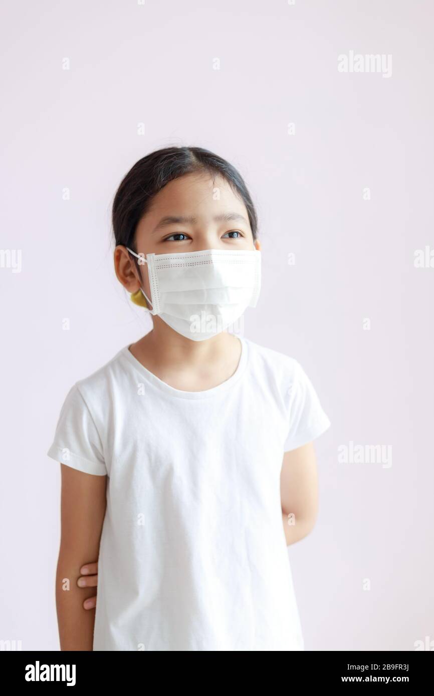 Portrait of Asian little girl wears a sanitary mask. The epidemic of the flu, Coronavirus or COVID-19 and illness. Stock Photo