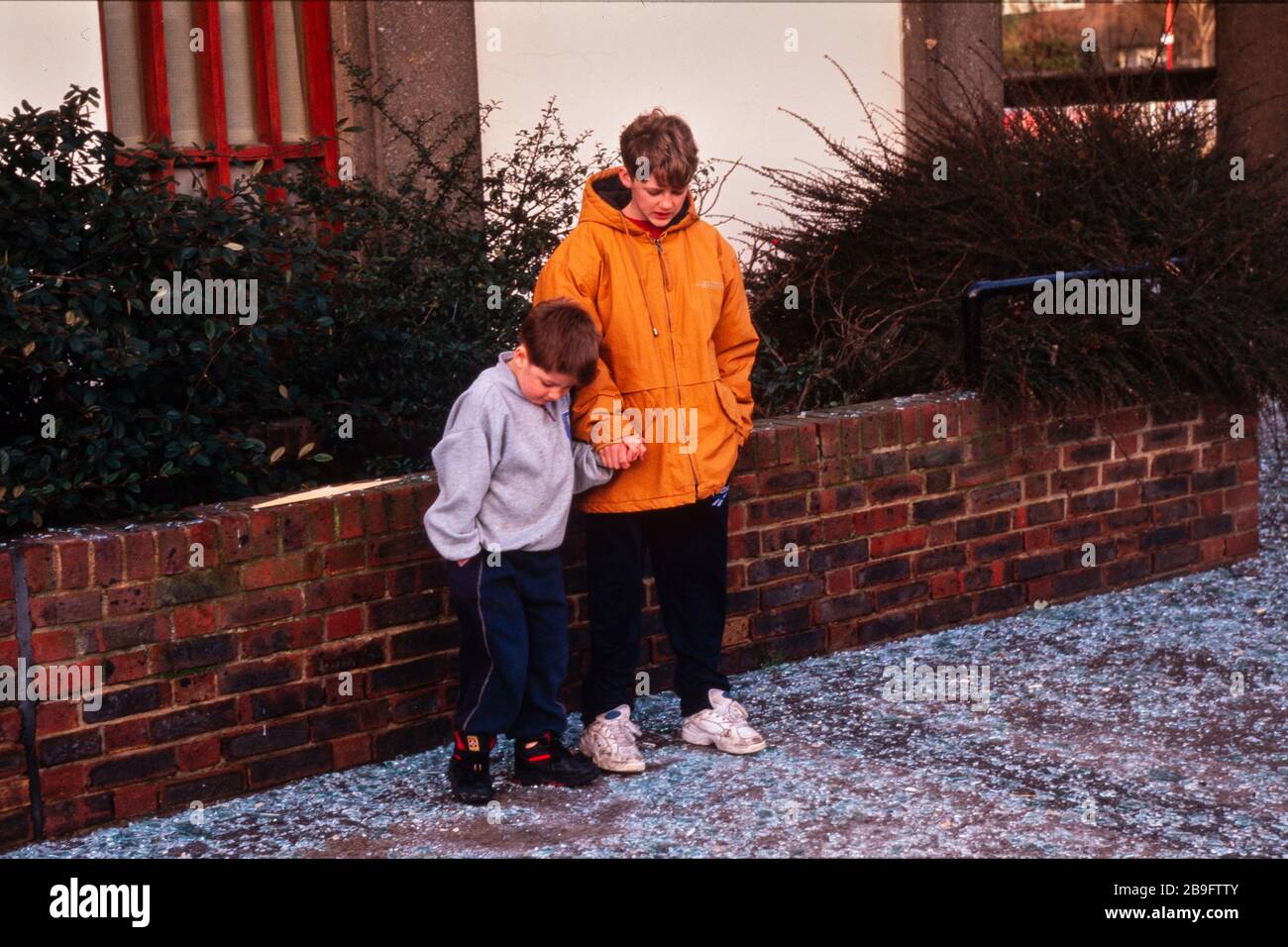 Local children draw patterns in the broken glass the day after the IRA detonated a powerful truck bomb in South Quay, London Docklands on 9 Feb 1996, the killing two & causing £150 million worth of damage. Stock Photo