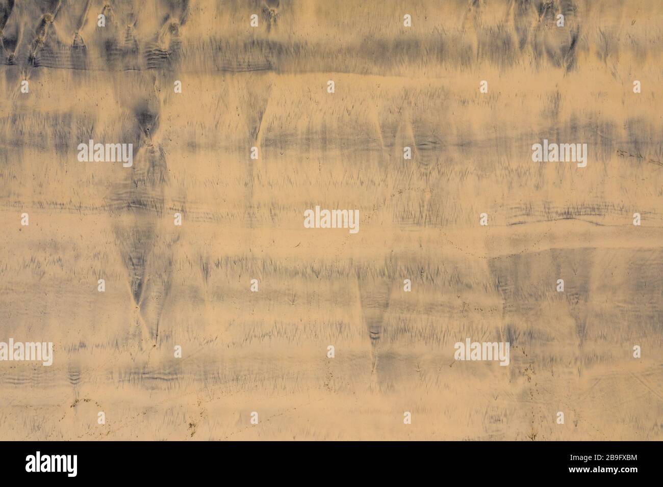 aerial photo of dark silty patterns left in the golden sand by the tide Stock Photo