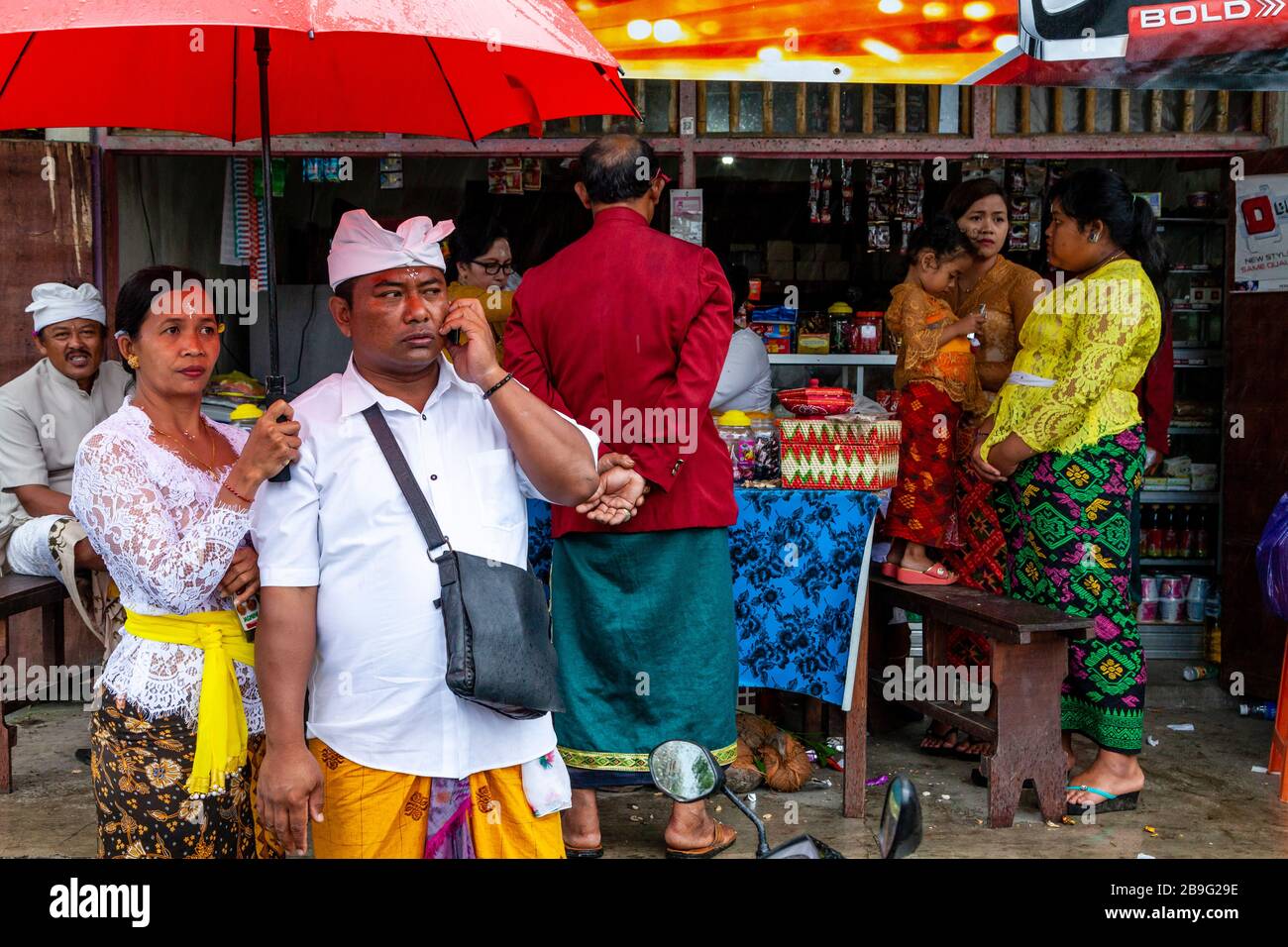 A Group Of Colourfully Dressed Balinese Hindu People Standing By A Street Food Stall During A Local Religious Festival, Ubud, Bali, Indonesia. Stock Photo