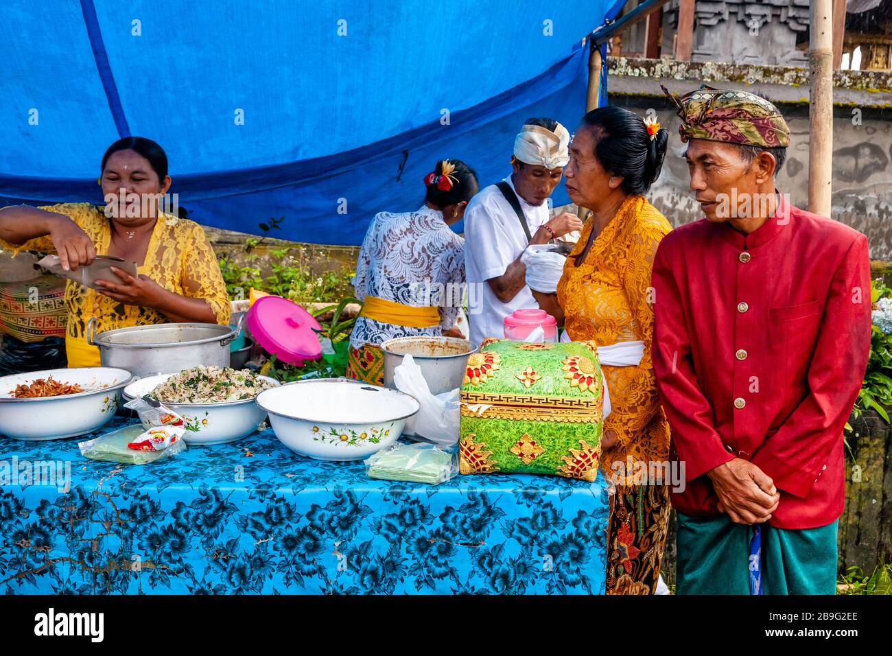 A Group Of Balinese Hindu People In Traditional Costume At A Street Food Stall During A Local Religious Festival, Ubud, Bali, Indonesia. Stock Photo