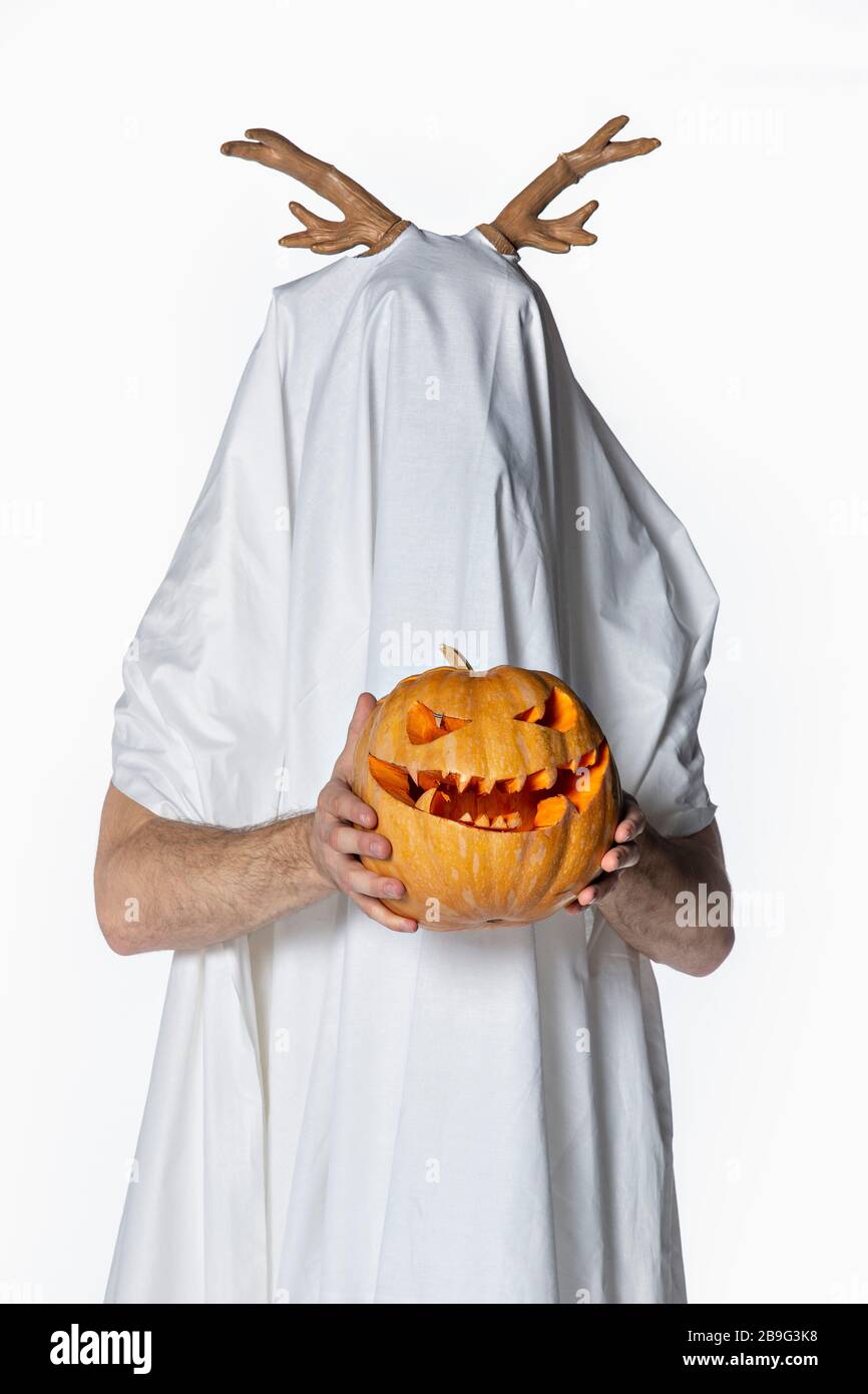 Portrait playful man in sheet costume holding jack o lantern Stock Photo