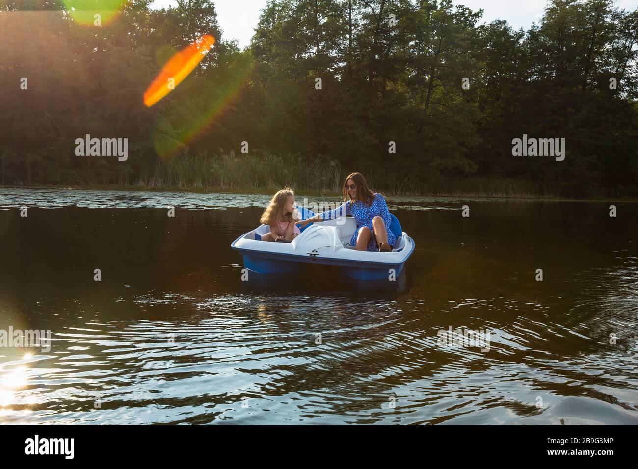 Mother and daughter paddleboating on sunny pond Stock Photo