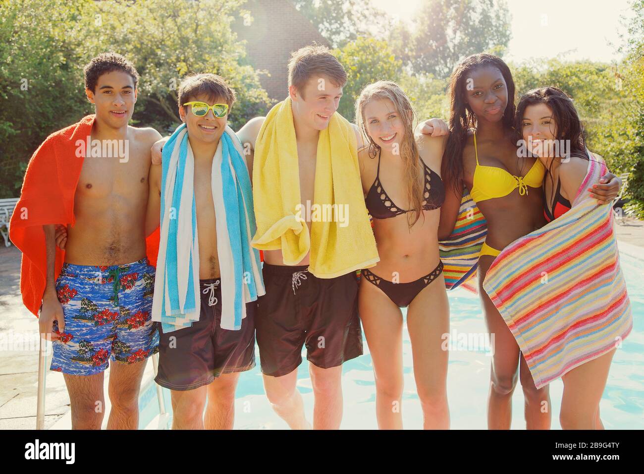 Portrait happy teenage friends at sunny summer poolside Stock Photo
