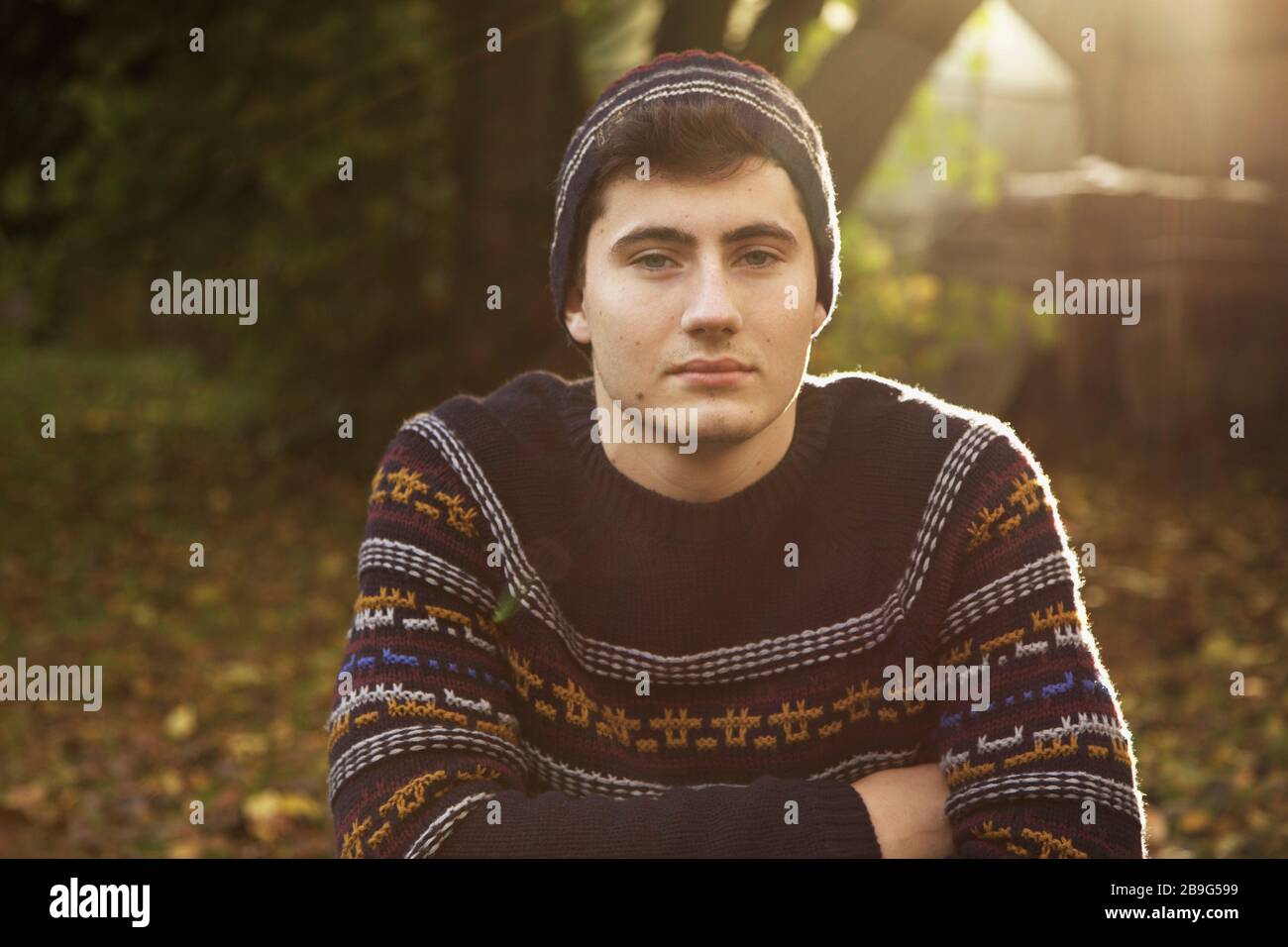 Portrait confident teenage boy in sweater and knit hat in autumn park Stock Photo