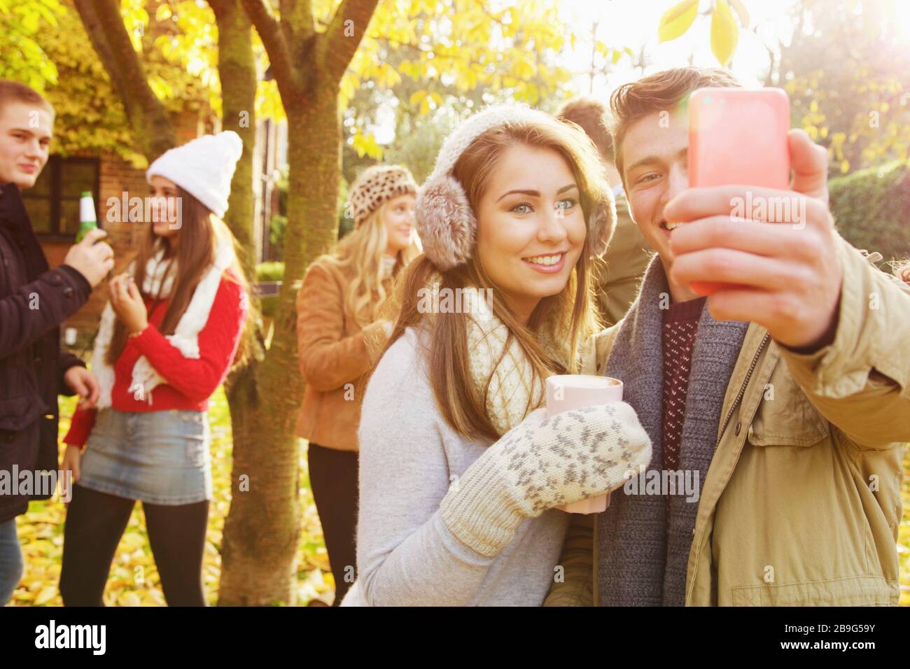 Happy teenage couple taking selfie with smart phone in autumn park ...