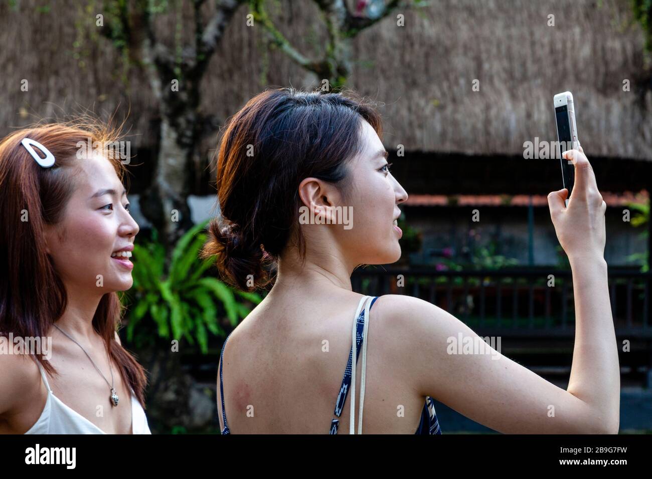 Asian Tourists Taking Photos At Pura Taman Saraswati, Bali, Indonesia. Stock Photo