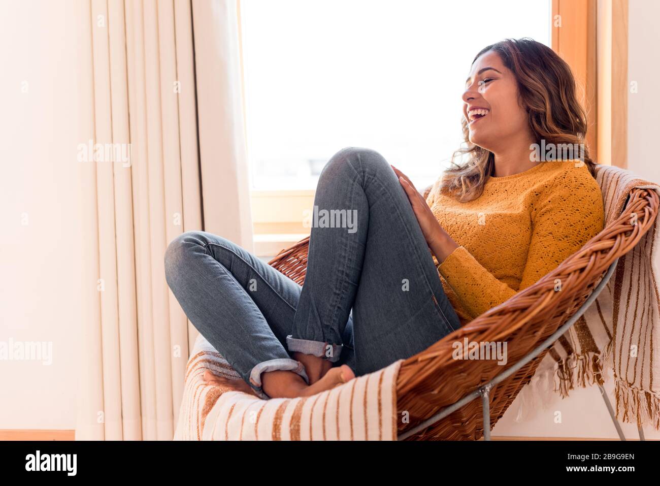 Optimistic woman sitting in a confortable rattan chair at home Stock Photo