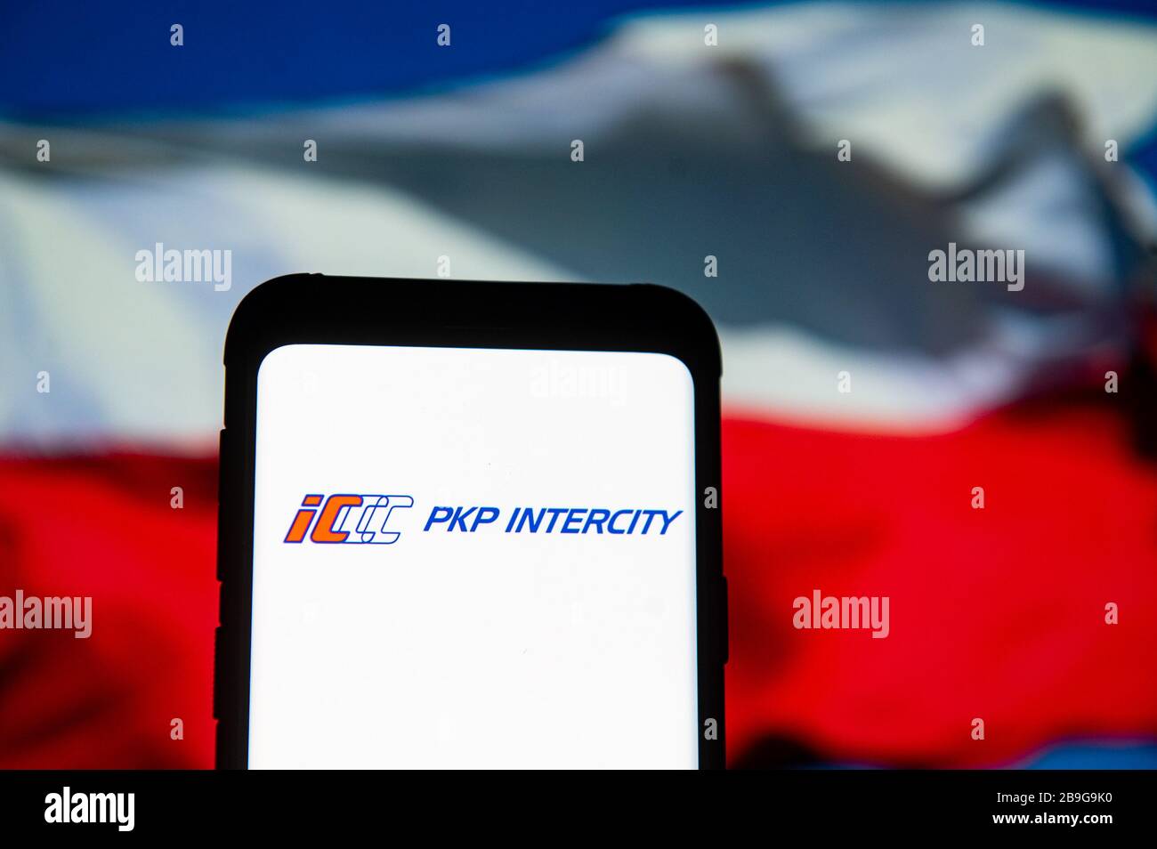 In this photo illustration a PKP Intercity logo seen displayed on a smartphone.The Polish national flag is displayed as the background. Stock Photo