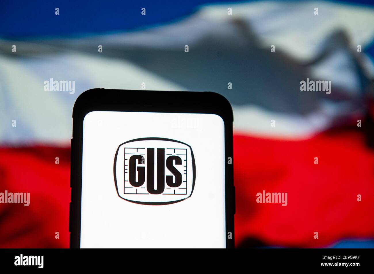 In this photo illustration a Glowny Urzad Statystyczny GUS logo seen displayed on a smartphone.The Polish national flag is displayed as the background. Stock Photo