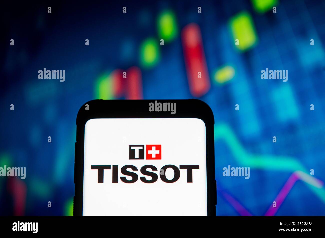 In this photo illustration a Tissot logo seen displayed on a smartphone.A stock market chart is being displayed as the background. Stock Photo
