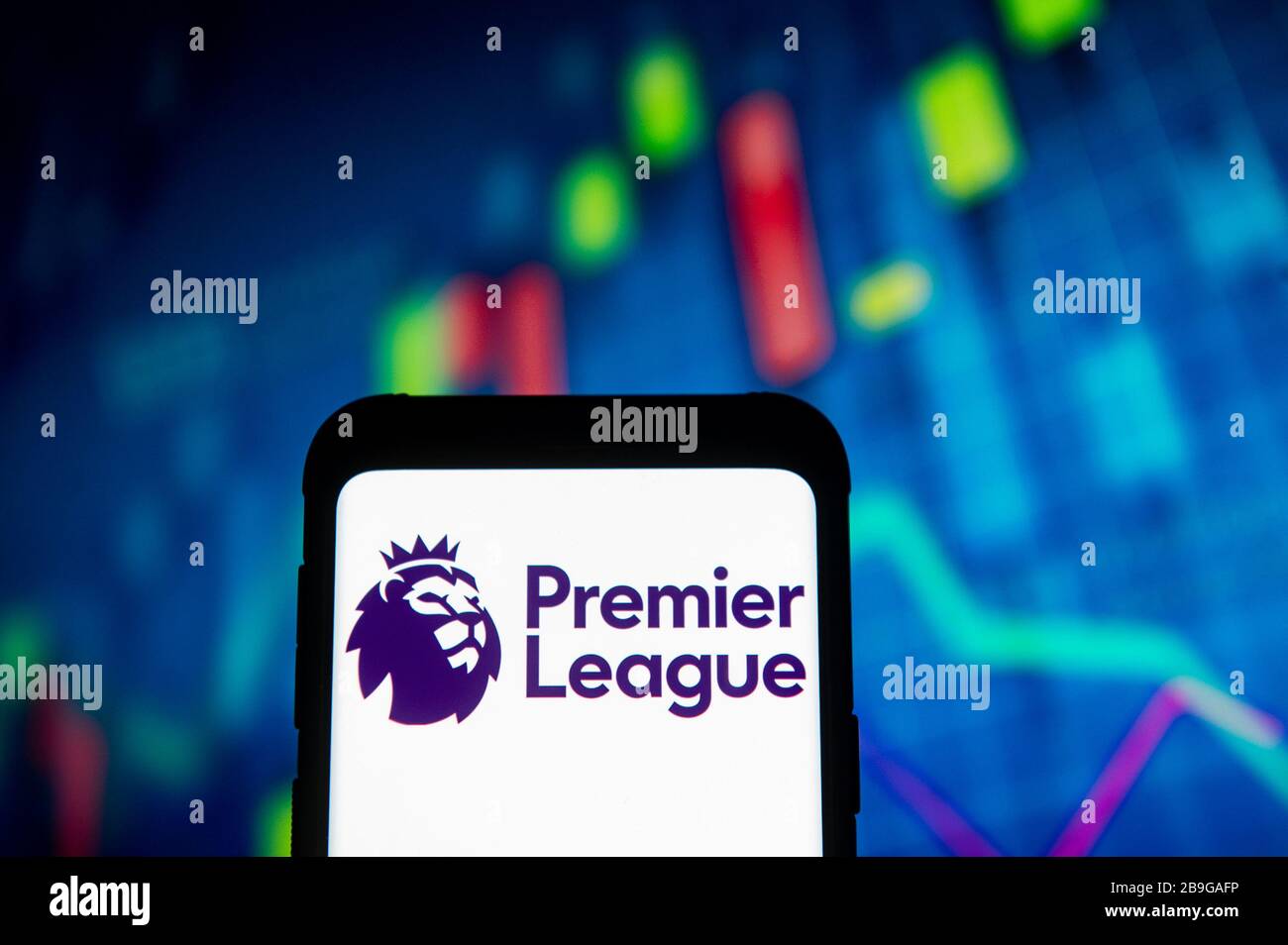 In this photo illustration a Premier League logo seen displayed on a smartphone.A stock market chart is being displayed as the background. Stock Photo