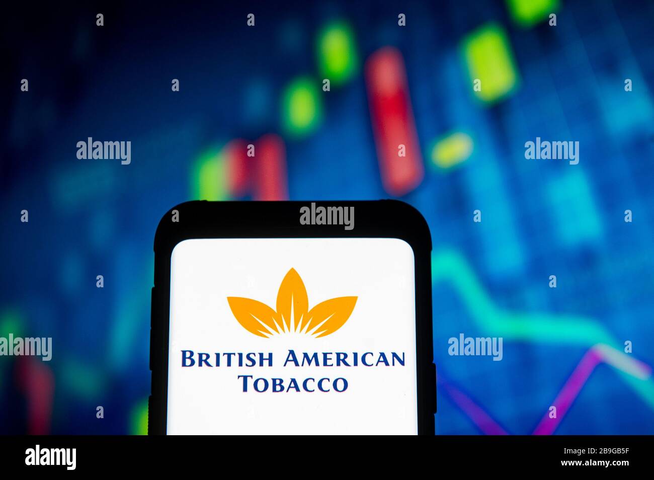 In this photo illustration a British American Tobacco logo seen displayed on a smartphone.A stock market chart is being displayed as the background. Stock Photo