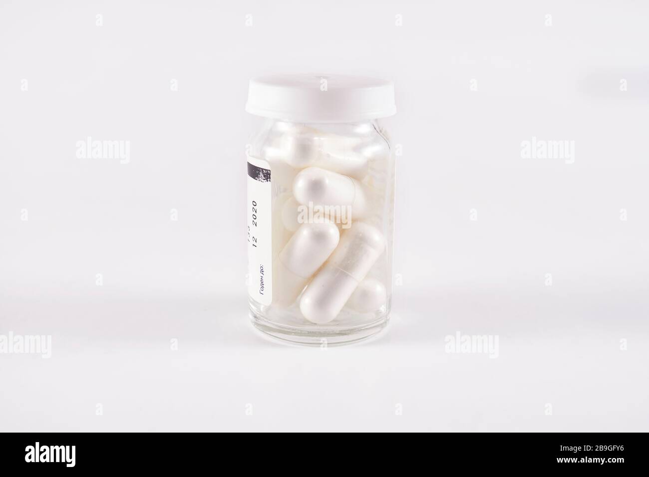 Glass pill bottle full of white capsules (frog eye view on white background) Stock Photo