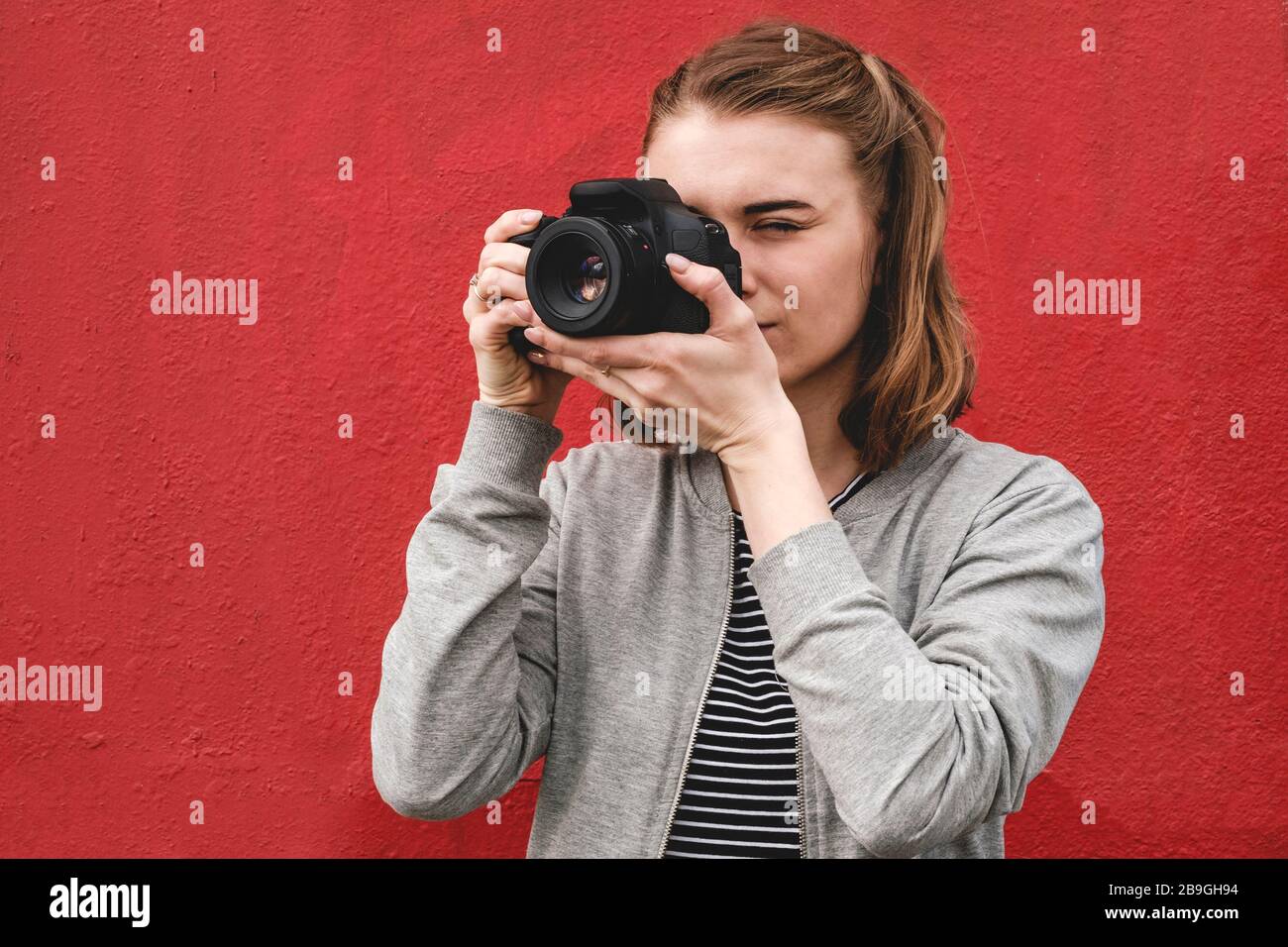 Young woman photographer focusing on the viewer Stock Photo
