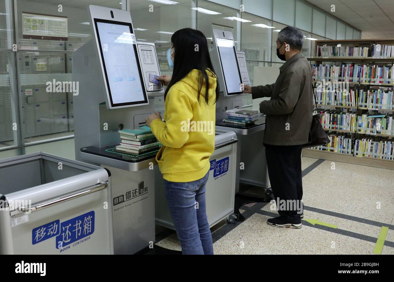 Hefei, China's Anhui Province. 24th Mar, 2020. Readers use self-service book returning machines to return books at Anhui Provincial Library in Hefei, east China's Anhui Province, March 24, 2020. The library reopened on Tuesday under strict measures taken to fight against the COVID-19. It is allowed to receive no more than 1,200 readers per day and 220 people in real time. Readers are required to wear face masks, display their identity card or reader card, take temperature checking and verify their health QR code before entering the library. Credit: Han Xiaoyu/Xinhua/Alamy Live News Stock Photo