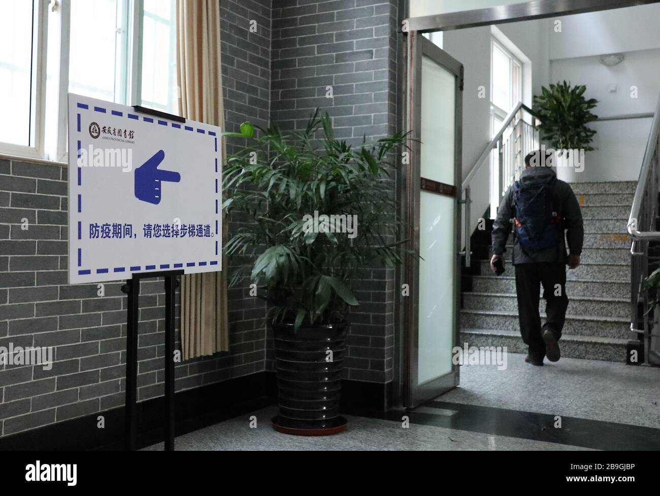 Hefei, China's Anhui Province. 24th Mar, 2020. A reader walks upstairs at Anhui Provincial Library in Hefei, east China's Anhui Province, March 24, 2020. The library reopened on Tuesday under strict measures taken to fight against the COVID-19. It is allowed to receive no more than 1,200 readers per day and 220 people in real time. Readers are required to wear face masks, display their identity card or reader card, take temperature checking and verify their health QR code before entering the library. Credit: Han Xiaoyu/Xinhua/Alamy Live News Stock Photo