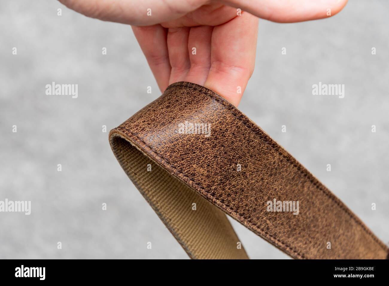 Brown natural cow leather strap hanging over some fingers Stock Photo