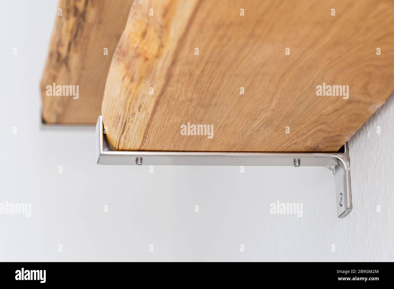 Shelves made by natural oak planks mounted with brushed steel attachment to the wall Stock Photo
