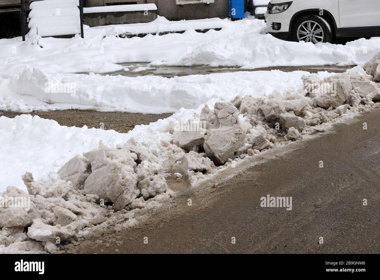 Uncleaned streets with heavy snowdrifts after snowfall in the city, cars under the snow. Stock Photo