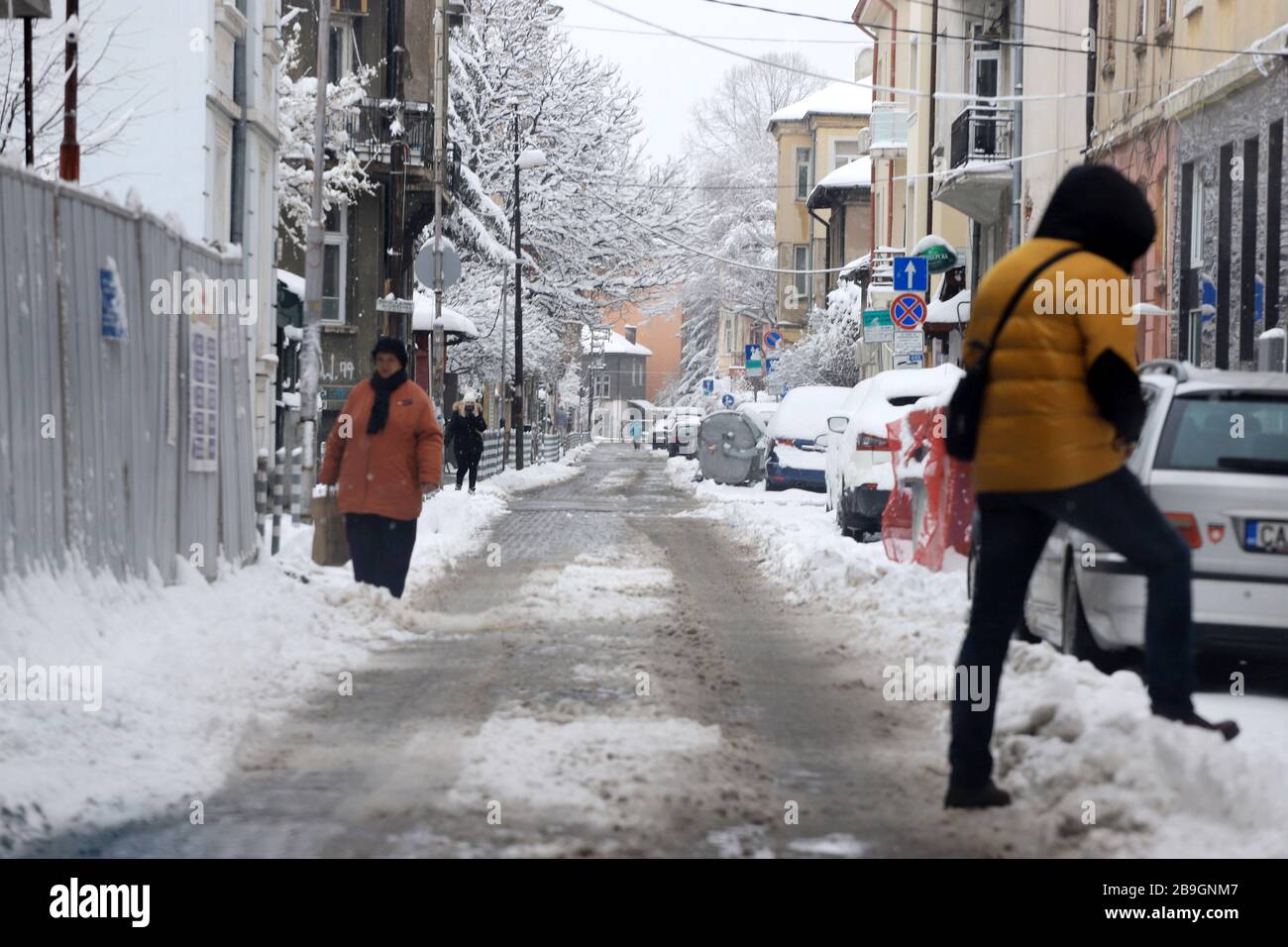 People walk in snow drifts on uncleaned street, after snow blizzard in Sofia, Bulgaria on march 24, 2020 Stock Photo