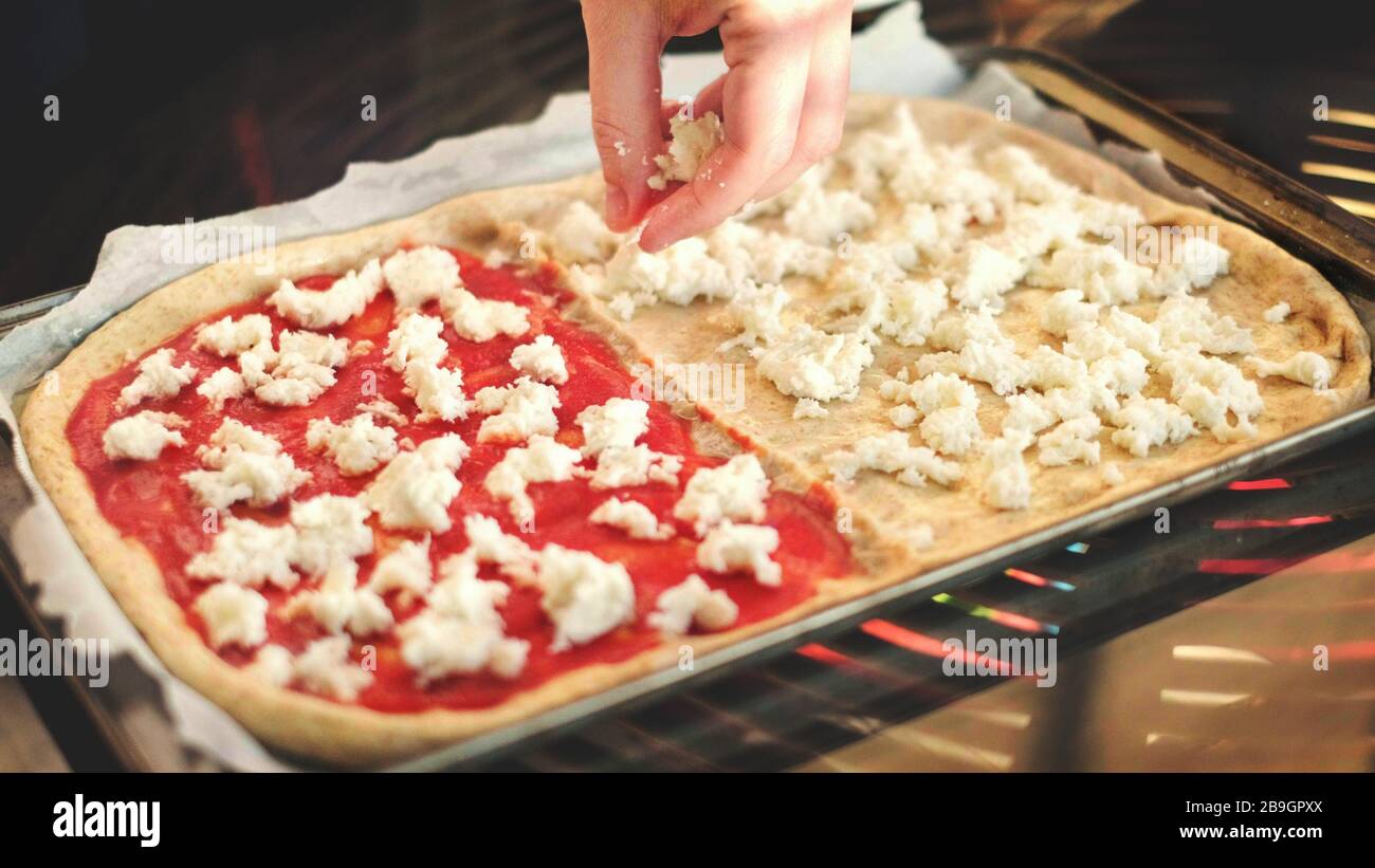 homemade rustic pizza italian cookery background - hands put mozzarella on bakin sheet Stock Photo