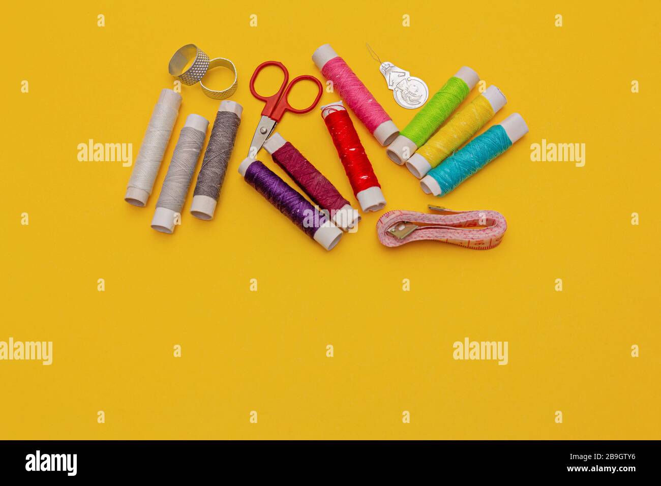 Thread, needles, scissors and meter on yellow background. tailoring set. sewing kit Stock Photo