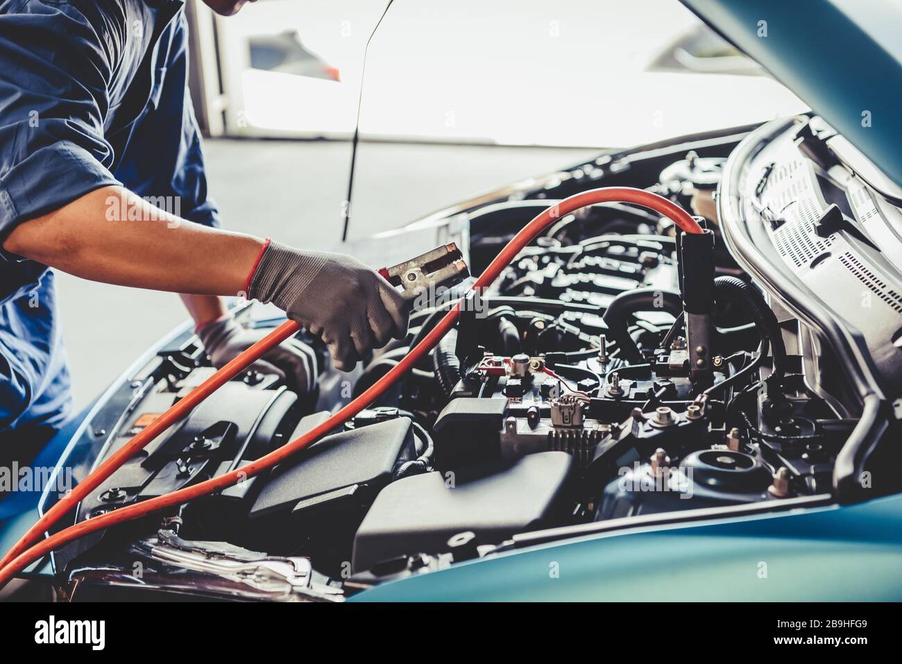 Car mechanic holding battery electricity trough cables jumper and