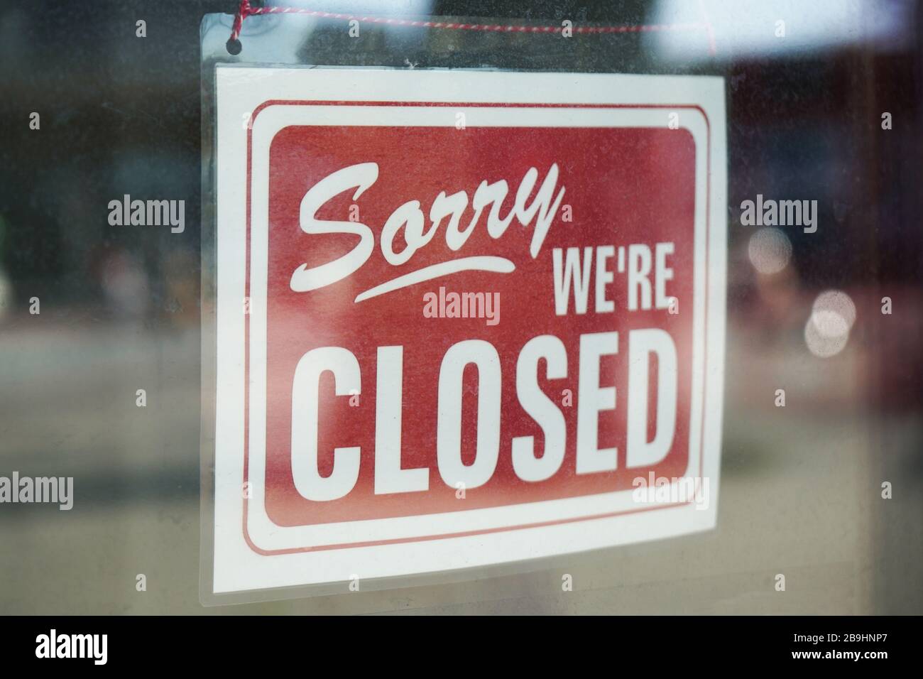 Sorry we're closed sign behind dirty glass door during corona lockdown Stock Photo