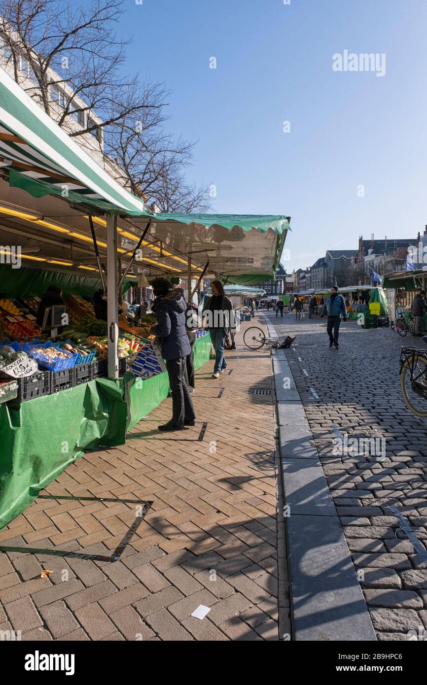People on the farmer's market in Groningen in the Netherlands keeping social distance by waiting in special outlined spaces during the outbreak of the Stock Photo