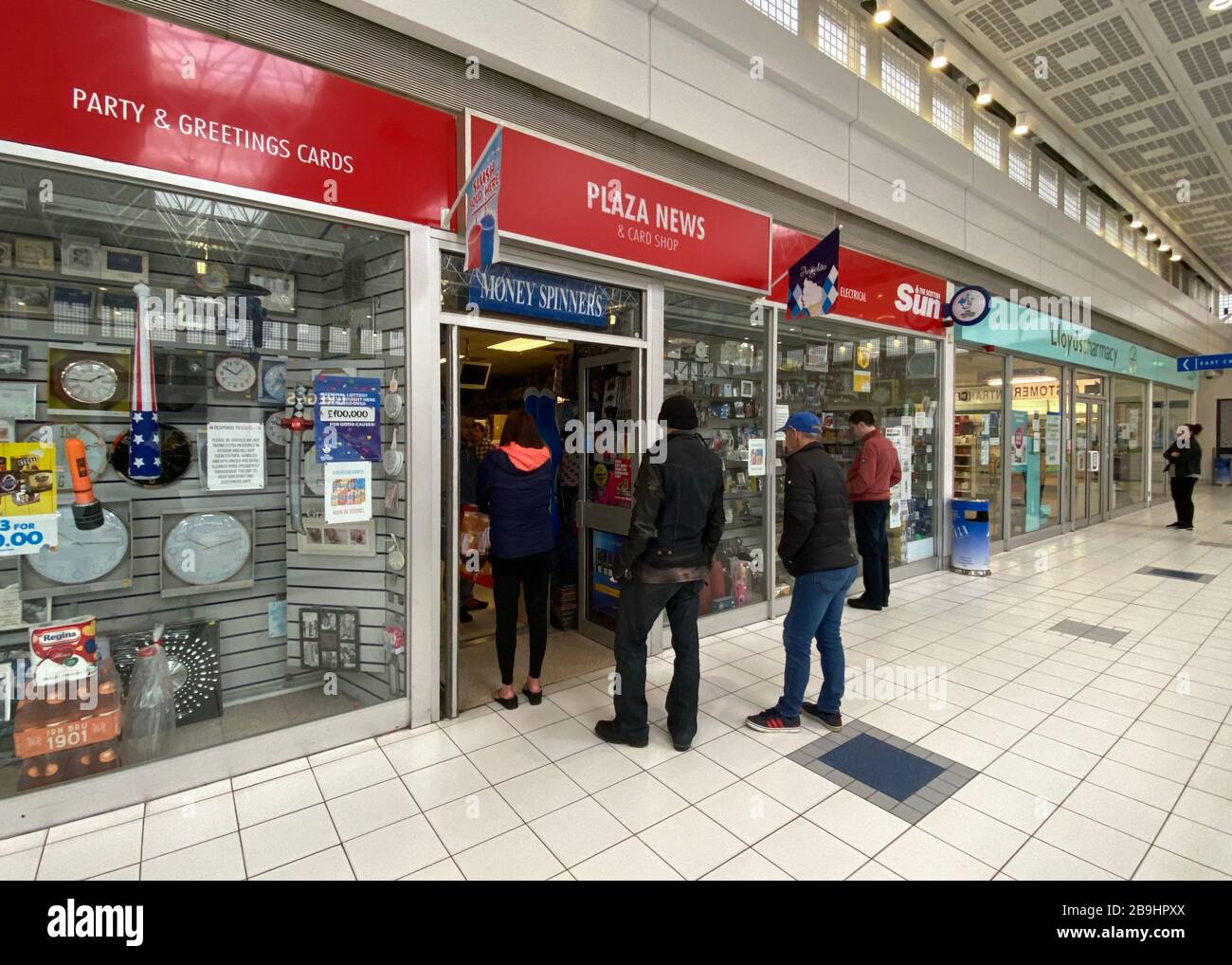 People queueing outside a newsagent in a shopping mall on first day of coronavirus lockdown Stock Photo