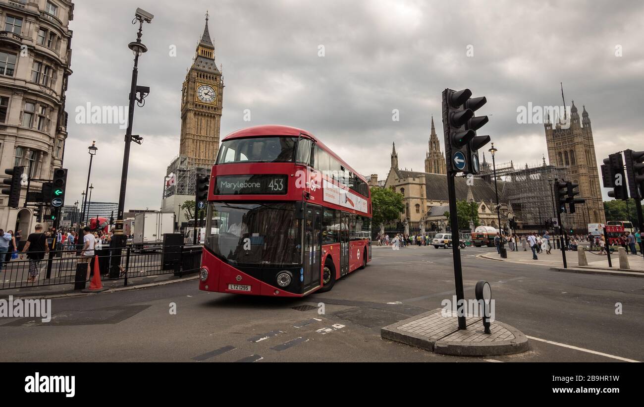 A red London bus at Parliament Square, Westminster. Background landmarks include the Houses of Parliament and Big Ben. Stock Photo