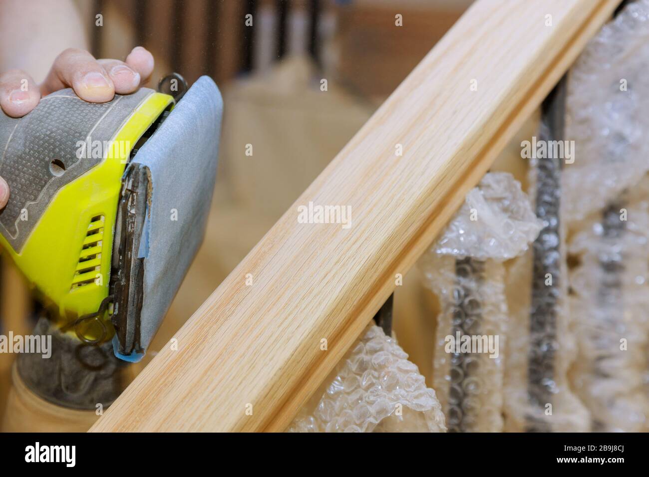 Wooden railing sanding with sandpaper for stairs grinder work in the