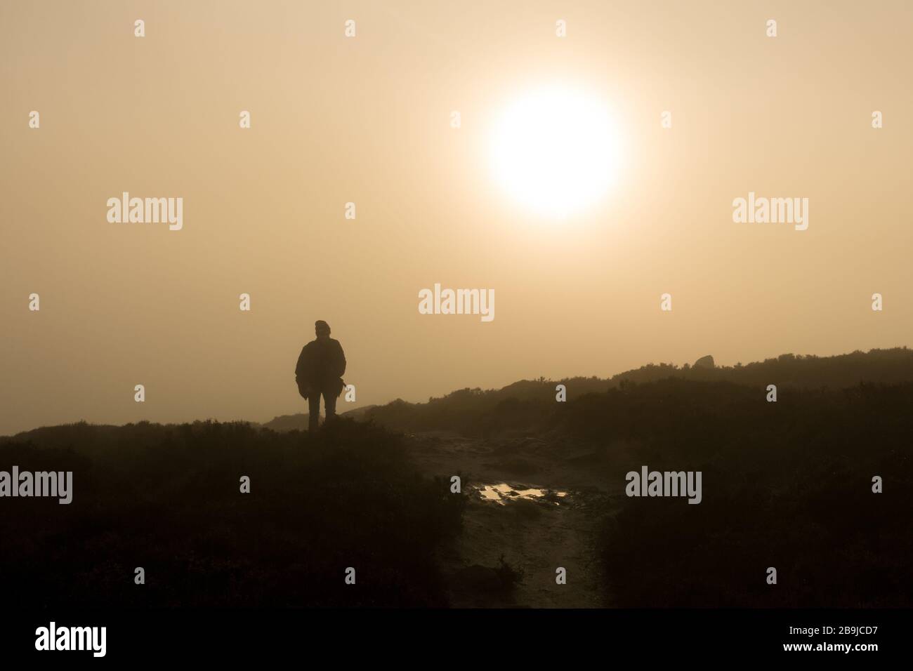 Atmospheric view of a person walking out of a foggy valley into the sunshine in a cloud inversion in the countryside, Ilkley Moor, West Yorkshire, UK Stock Photo
