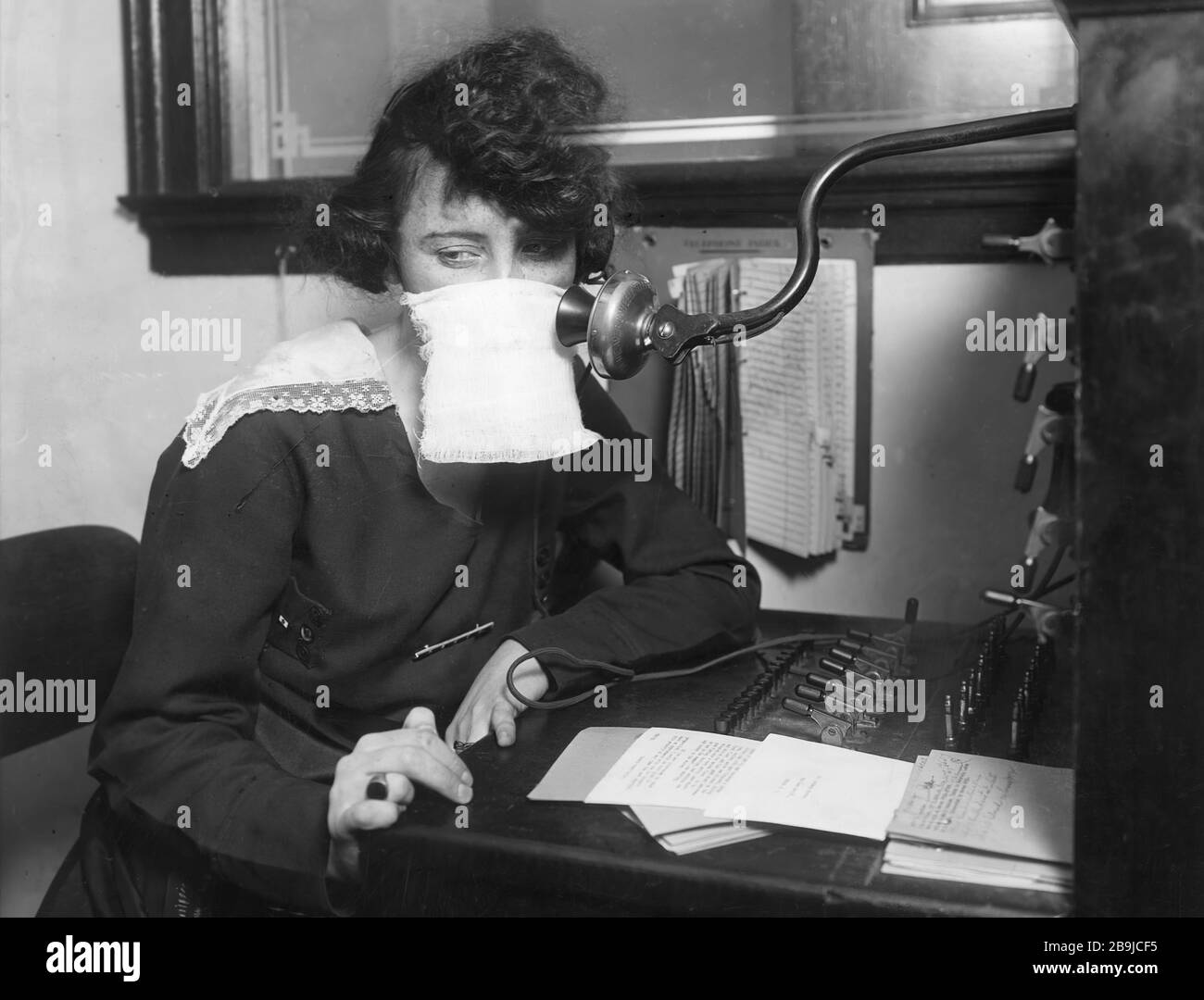 (Original Caption) Flu epidemic, 1918: Telephone operater with protective gauze. 1918-1919. An epidemic of "Spanish Flu" spread around the world. At least 20 million died, although some estimates put the final toll at 50 million. Stock Photo