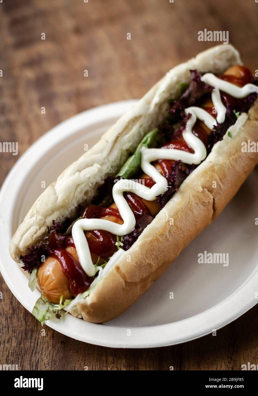 classic hot dog with frankfurter sausage and sauces on wood table Stock Photo