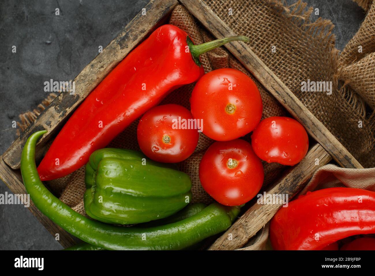 Red tomatoes and peppers in a rustic tray. Top view Stock Photo - Alamy