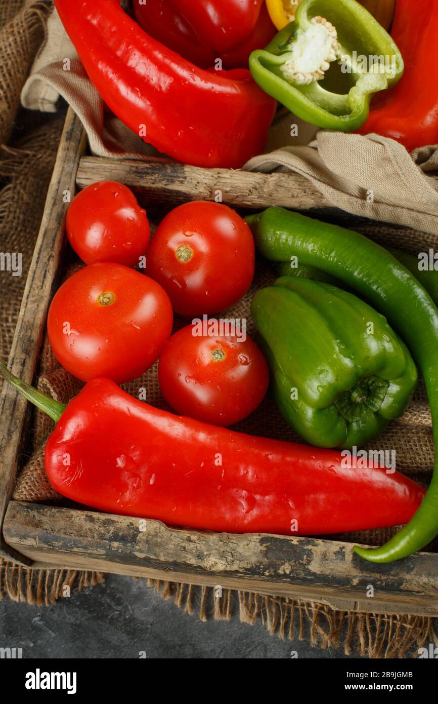 Red tomatoes and green peppers in a wooden container Stock Photo - Alamy