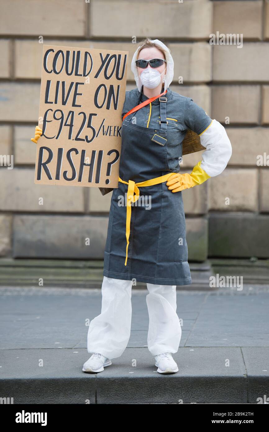 Edinburgh, UK. 23 March 2020.   Pictured: Protestor holding placard which says, “COULD YOU LIVE ON £94.25 / MONTH RISHI?” Protesting against the UK Chancellor, Rishi Sunak for freelancers and self employed people who are instructed by the government to stay at home due to the Coronavirus Pandemic. Self employed are currently not eligible for the chancellors stay at home emergency pay whilst employed people are to receive up to 80% of their sallary. Stock Photo