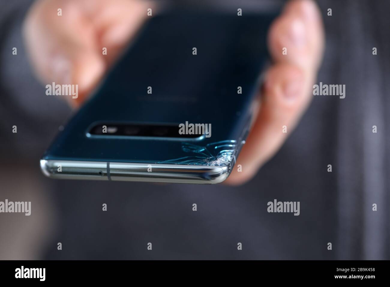 Man hold in hand modern smartphone with cracked corner Stock Photo