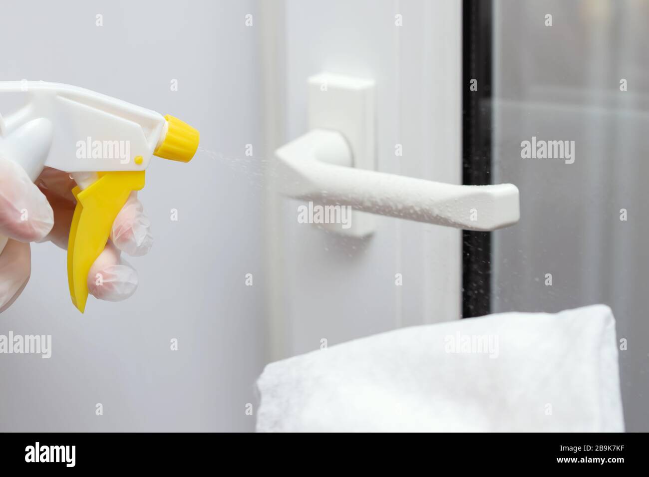 Actions to prevent the spread of coronavirus KOVID-19, disinfection of the door handle. Hand in gloves sprays disinfectant liquid on the handle Stock Photo