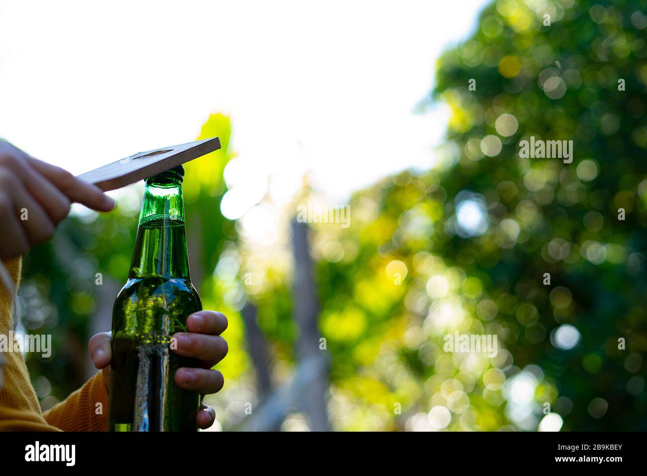 Opening a beer bottle with a bottle opener. Concept of opening a beer. Stock Photo