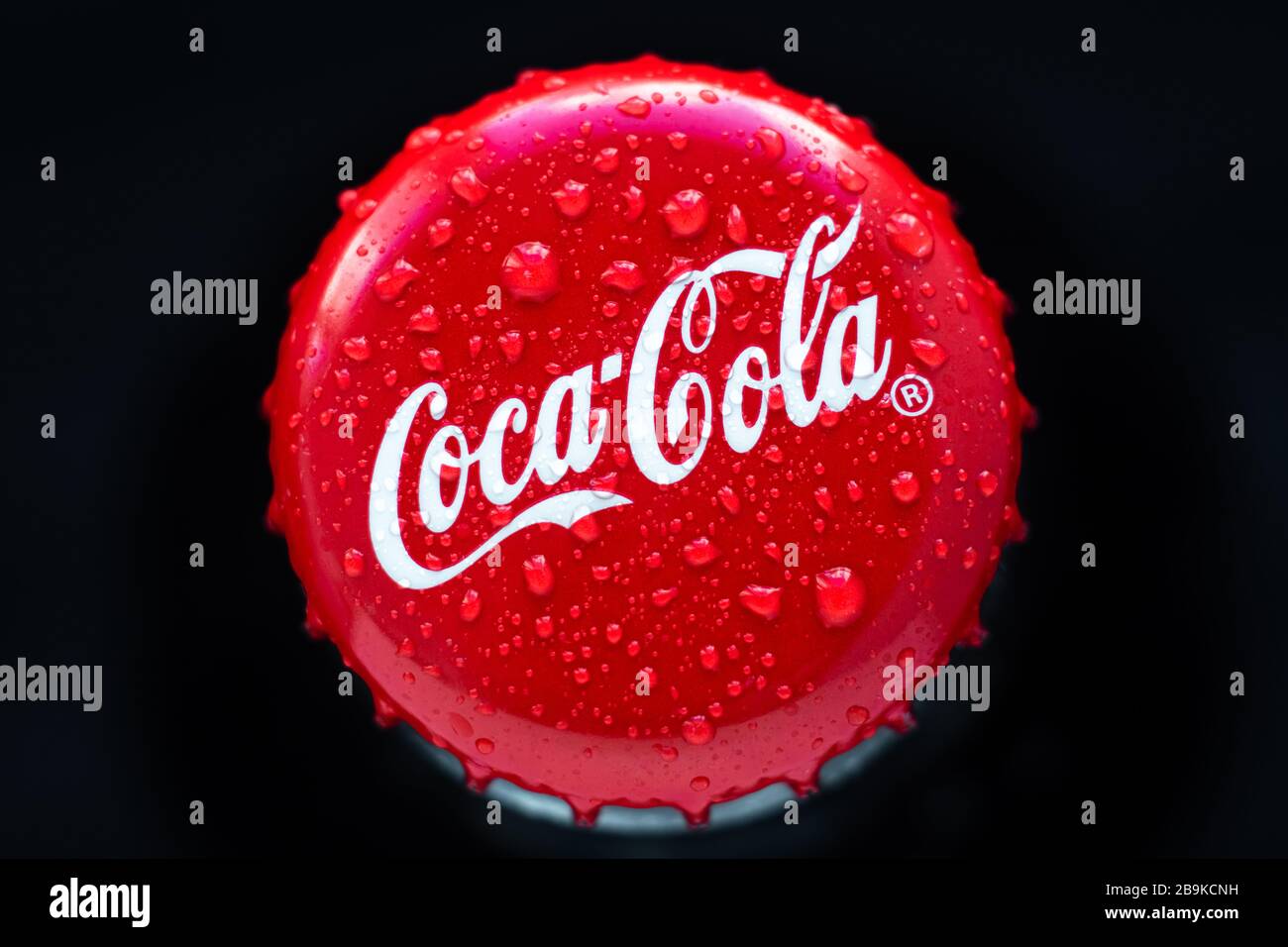 Kharkiv, Ukraine, March 22, 2020: Close-up cork of coca-cola on black background. Drops of water on original drink. Glass bottle of cola. Top view. Il Stock Photo