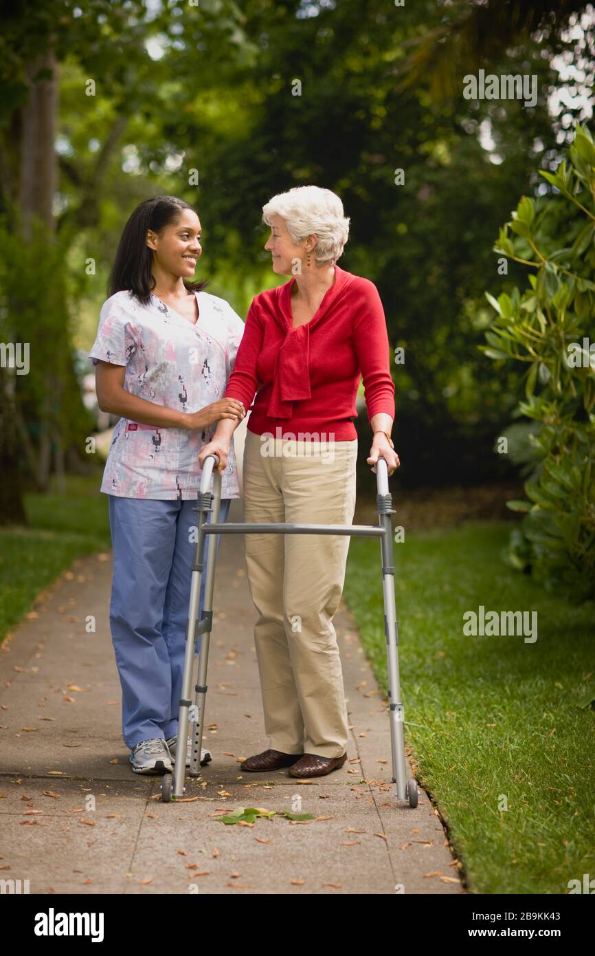 Young nurse assists senior woman with a walking frame Stock Photo - Alamy
